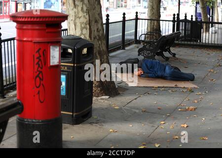 Ein obdachloser Mann, der auf der Brompton Road, London, Großbritannien, schlecht schläft. Stockfoto