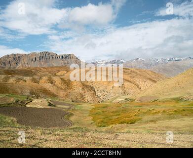 Terrassierte Felder gepflügt, flankiert von hügeliger Landschaft und Schnee gipfelte Himalaya und blauen Himmel im Sommer in der Nähe Komic Dorf, Himachal Pradesh, Indien. Stockfoto