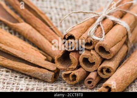 Zimtstangen, trockene Zimtrinde in einem Bündel auf einem Sackleinen Hintergrund gebunden. Stockfoto