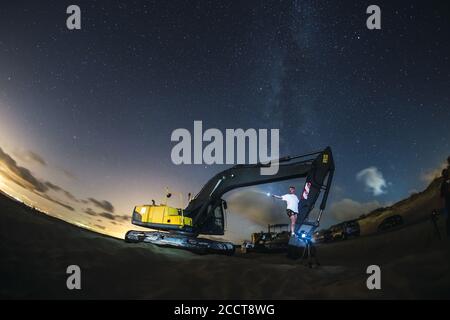 Bagger arbeiten unter dem Nachthimmel mit der Milchstraße in Valdevaqueros, Cadiz, Andalusien Stockfoto