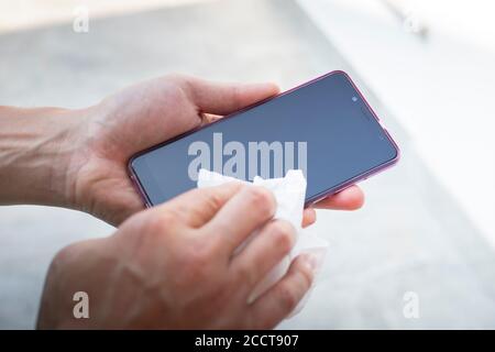 Männliche Hände wischen Smartphone-Bildschirm mit einem weißen Tuch. Stockfoto