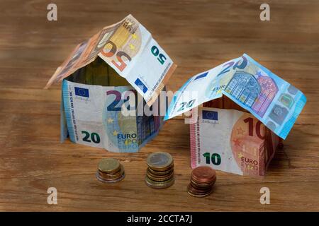 Zwei Häuser aus 50, 20 und 10 Euro Banknoten mit Stapel von Euro-Münzen Stockfoto