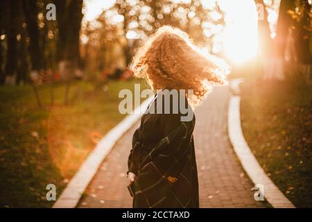 Junge Rotkopffrau, die beim Spaziergang im Park Haare wirft Im Herbst Stockfoto