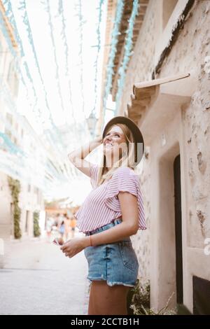 Glückliche blonde Frau mit Hut genießen Tourismus auf Mallorca Stockfoto