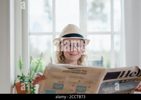 Junges Mädchen zieht lustige Gesichter beim Lesen einer Zeitung Stockfoto