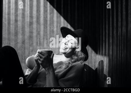 Frau saß lachend während sie Kaffee in einem Café trank Stockfoto