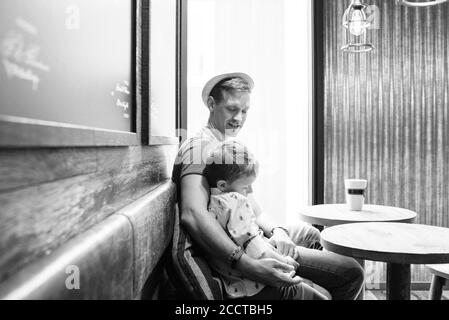 Vater saß kuscheln seinen Sohn während Kaffee trinken in einem Café Stockfoto