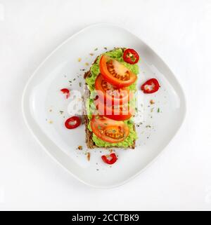 Köstlicher Avocado-Toast mit Tomaten und Vollkornbrot auf weißem Hintergrund. Gesunde Ernährung Konzept. Draufsicht. Stockfoto