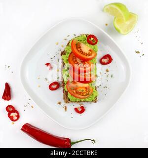 Köstlicher Avocado-Toast mit Tomaten und Vollkornbrot auf weißem Hintergrund. Gesunde Ernährung Konzept. Draufsicht. Stockfoto