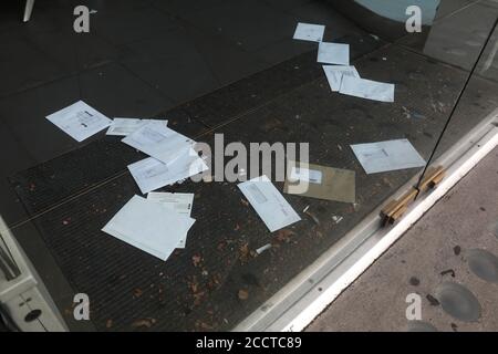 Briefe und Rechnungen stapeln sich auf der Türmatte eines geschlossenen Ladens an der Brompton Road, London, Großbritannien. Stockfoto