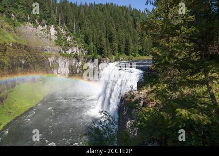 Ein Regenbogen im Nebel der Upper Mesa Falls Es stürzt über eine Klippe in die zerklüftete Wildnis von Henrys Fork des Snake River entlang der Mesa Falls Stockfoto