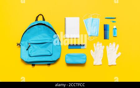 Zurück zur Schule in Pandemiekonzept. Schulbedarf, eine leere Schultasche und Schutzausrüstung, Masken, Handschuhe und Desinfektionsmittel. Neue Normalität in der Schule. Stockfoto