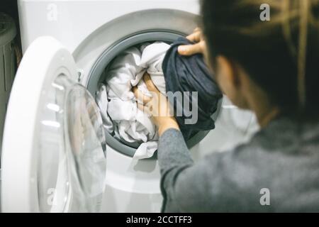 Eine Frau oder Hausfrau lädt oder legt die Wäsche in die Spülmaschine zum Waschen. Stockfoto