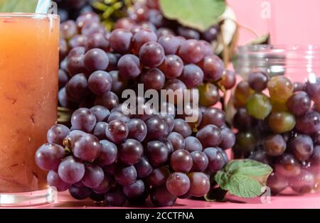 Topf mit Körnern und Traubentrauben. Traubensaft. Erfrischendes Getränk. Fruchtgetränk. Zutat für Weine und Säfte. Frisches Obst. Rosafarbene Traube. Stockfoto