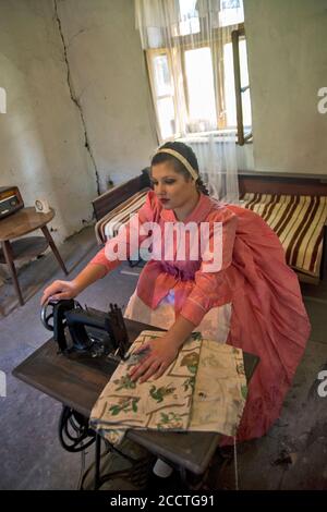 Ivanovo, Serbien, 09. April 2017. Ein Mädchen in einem Raum sitzt hinter einer Nähmaschine und näht. Ihre Gedanken wanderten zu ihrem Freund. Stockfoto