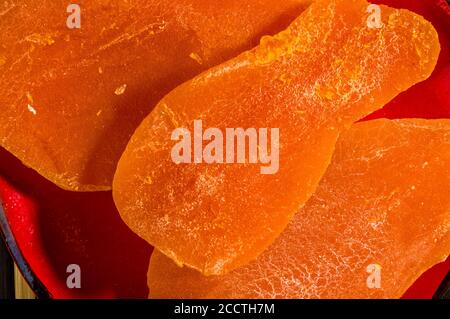 Scheiben getrocknete Mango in einer roten Untertasse auf einer Bambusmatte, Nahaufnahme. Stockfoto