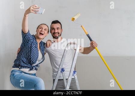 Ein verheiratetes Paar nimmt ein Selfie am Telefon, während Sie machen Reparaturen Stockfoto