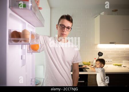 Kamera im Inneren Küche Kühlschrank: Mann öffnet Kühlschranktür, sieht innen. Stockfoto