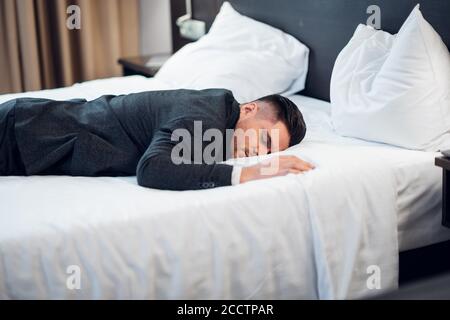 Ein Geschäftsmann, der im Hotelzimmer schläft. Müde nach einem langen Arbeitstag Stockfoto