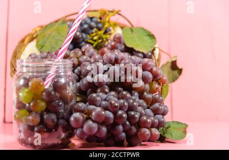 Topf mit Körnern und Traubentrauben. Traubensaft. Erfrischendes Getränk. Fruchtgetränk. Zutat für Weine und Säfte. Frisches Obst. Rosafarbene Traube. Stockfoto