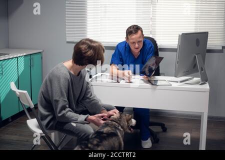 Eine Person mit einem Husky Hund mit einem Termin in einer Tierarztklinik. Stockfoto