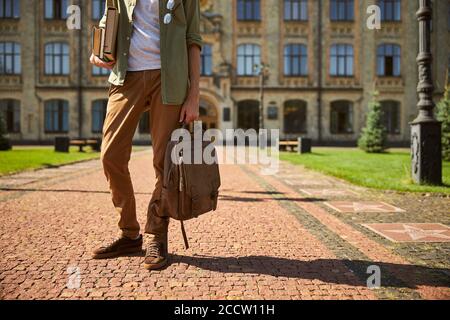 Mann, der einen Stapel Bücher und seinen Rucksack hält Stockfoto