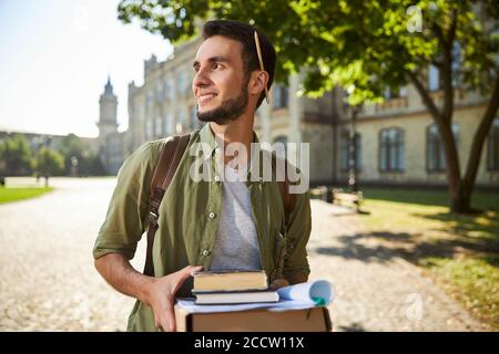 Fröhlicher Mann mit Lehrbüchern auf dem Universitätscampus Stockfoto