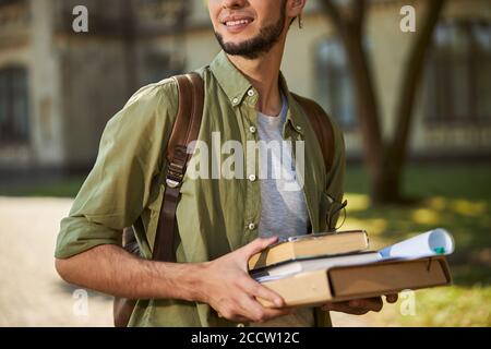 Lächelnder Student mit akademischer Literatur, die draußen steht Stockfoto