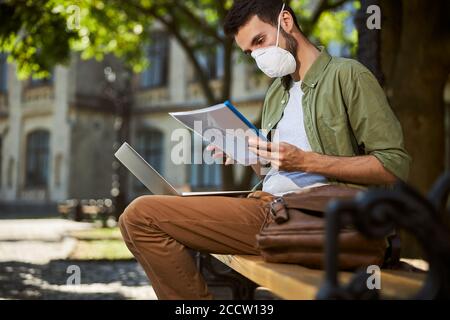 Undergraduate macht seine Hausaufgaben auf der Bank Stockfoto