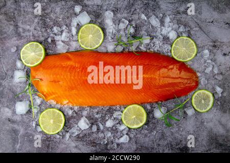 Frisches, rohes Lachsfischsteak mit Gewürzen auf Eis auf dunklem Steingrund. Kreatives Layout aus Fisch, Draufsicht, Flachlage Stockfoto