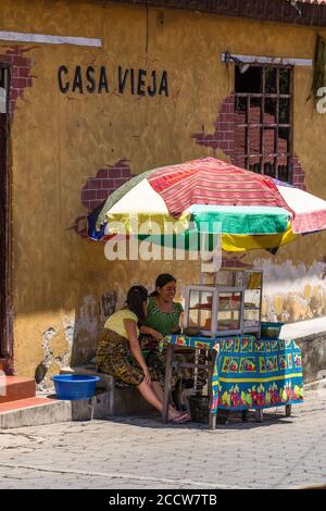 Tzutujil Maya Frauen in traditioneller Kleidung verkaufen Obst an einem Stand auf einer Straße in San Juan la Laguna, Guatemala. Stockfoto