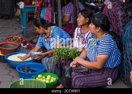 Drei Tzutujil Maya Frauen in traditioneller Kleidung verkaufen Produkte auf dem wöchentlichen offenen Markt in Santiago Atitlan, Guatemala. Stockfoto