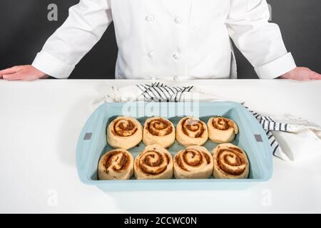 Ungebackene Zimtbrötchen in einer blauen Backform. Stockfoto