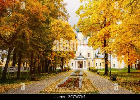 Alte christliche Kirche unter gelben Herbstbäumen. Schöne Kuppeln, hoher Glockenturm gegen den Himmel Stockfoto