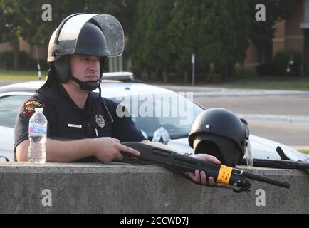 Kenosha, Wisconsin, USA. August 2020. Ein Polizeibeamter der Stadt Kenosha wacht am Montagabend, dem 24. August 2020, zwei Stunden vor der Ausgangssperre um 20 Uhr, über das öffentliche Sicherheitsgebäude des Bezirks Kenosha, während die Demonstranten zwei Blocks weiter im Bezirksgericht mit der Polizei konfrontiert sind, nachdem Jacob Blake, ein afroamerikanischer Mann, erschossen wurde. Von einem weißen Polizisten am Tag zuvor. Kredit: ZUMA Press, Inc./Alamy Live Nachrichten Stockfoto