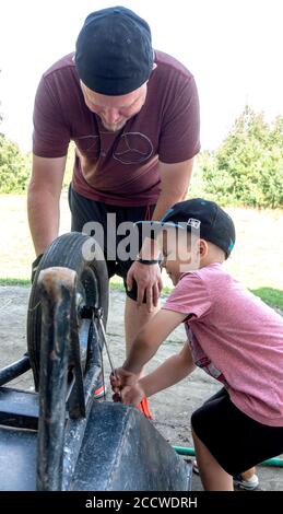 Vater und Sohn reparieren das Rad auf der Schubkarre. Zawady Gmina Rzeczyca Polen Stockfoto