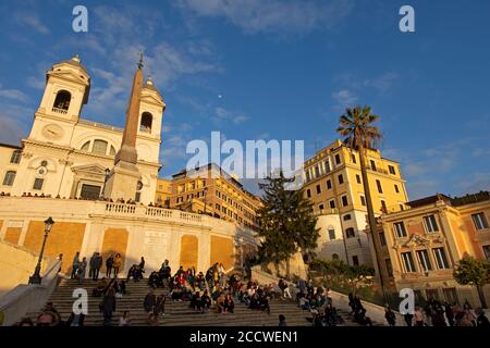 Die Menschen genießen den Sonnenuntergang auf der spanischen Treppe vor der Kirche Trinita dei Monti auf der Piazza di Spagna, Rom, Italien Stockfoto