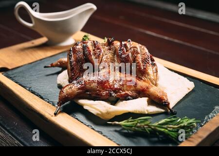 Gegrillte Wachteln auf Holzplatte in einem Restaurant Stockfoto