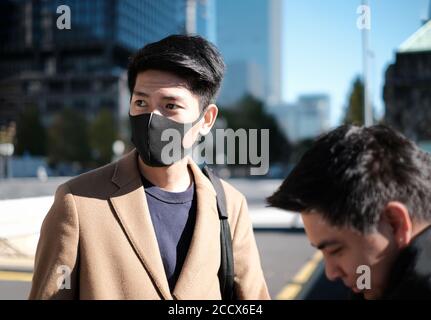 Junge asiatische Mann tragen schützende Gesichtsmaske und auf der Suche nach Der Ort zum Reisen Stockfoto