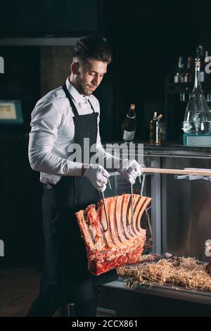 Der Kellner oder Koch bekommt trockenes Fleisch im Kühlschrank. Stockfoto