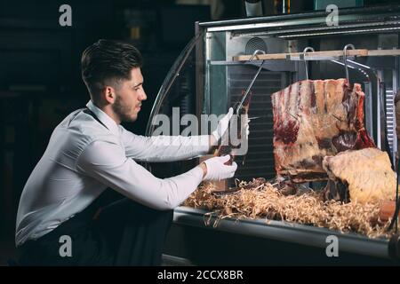 Der Kellner oder Koch bekommt trockenes Fleisch im Kühlschrank. Stockfoto