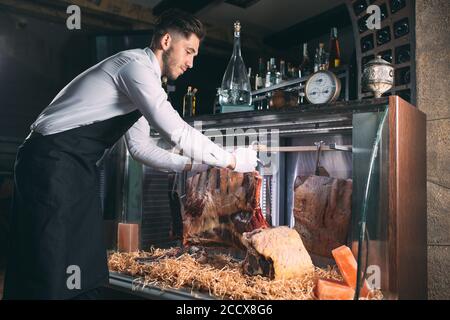Der Kellner oder Koch bekommt trockenes Fleisch im Kühlschrank. Stockfoto