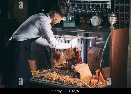 Der Kellner oder Koch bekommt trockenes Fleisch im Kühlschrank. Stockfoto