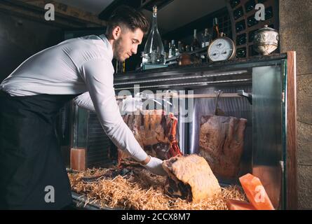 Der Kellner oder Koch bekommt trockenes Fleisch im Kühlschrank. Stockfoto