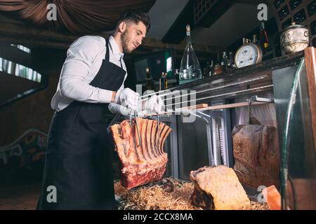 Der Kellner oder Koch bekommt trockenes Fleisch im Kühlschrank. Stockfoto