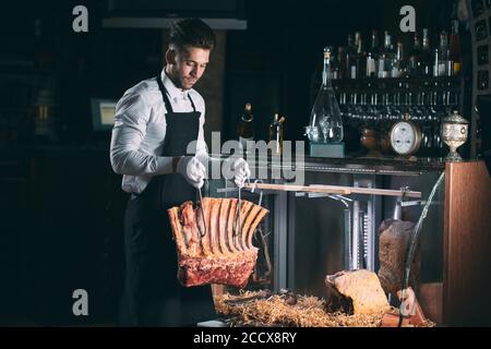 Der Kellner oder Koch bekommt trockenes Fleisch im Kühlschrank. Stockfoto