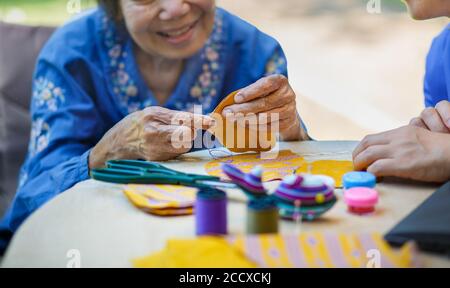 Ältere Frau mit Betreuer in der Nadel Handwerk Ergotherapie für Alzheimer oder Demenz Stockfoto