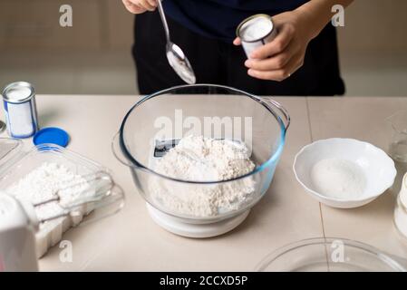 Frau Zugabe von Bikarbonat Soda Mehl in einer kleinen Küche Kalk beim Plätzchen in der Küche zu Hause Nahaufnahme Stockfoto