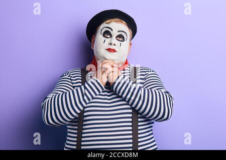 Portrait von fetten Pantomime Mann vortäuscht beten auf blauem Hintergrund. Kopieren Raum. Freude, Spaß, Komödie. Stockfoto