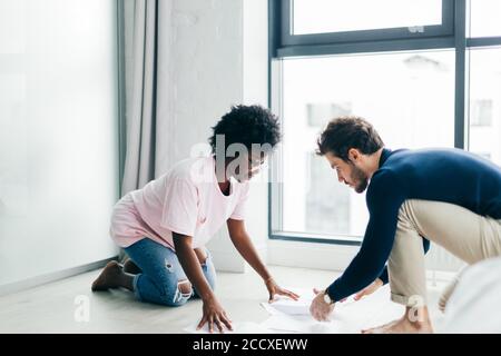 Junge multirassische Familienpaar sitzen auf dem Boden in geräumigen Wohnung, Rechnungen überprüfen, Studiendokumente, bereiten Finanzbericht Familie Beziehung und comm Stockfoto